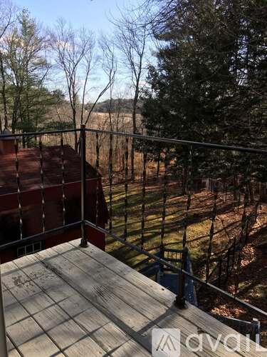 A balcony with a railing and a view of a field and trees.