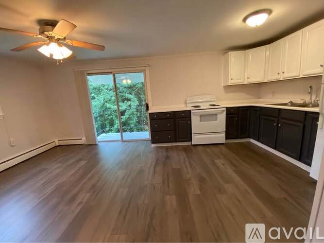 A kitchen with a white stove top oven and black cabinets.