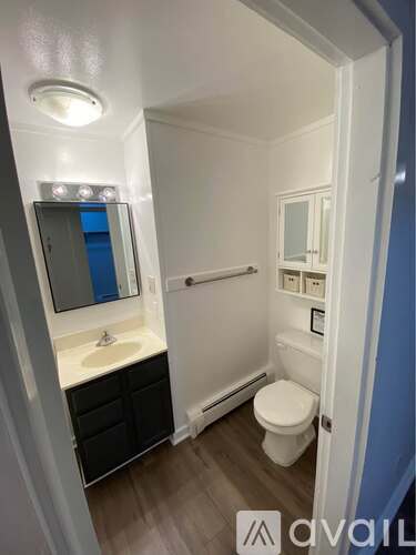 A bathroom with a toilet, sink, and mirror.