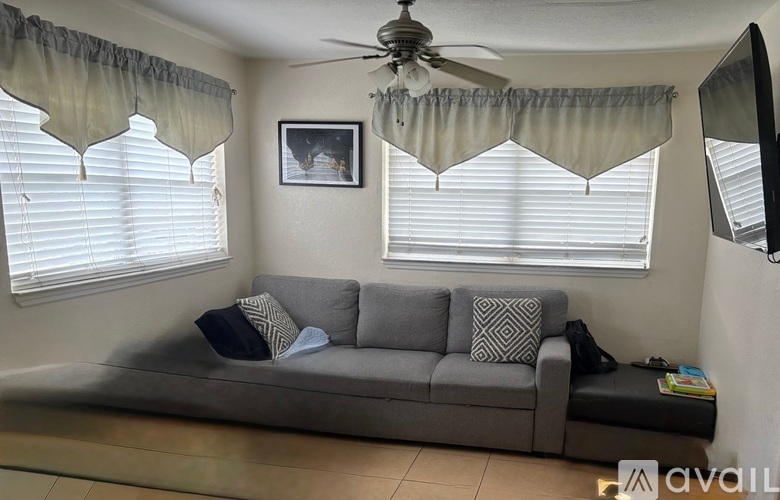 A living room with a grey couch and a ceiling fan.