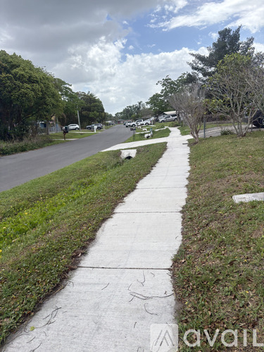 A sidewalk runs parallel to a road with a grassy median.