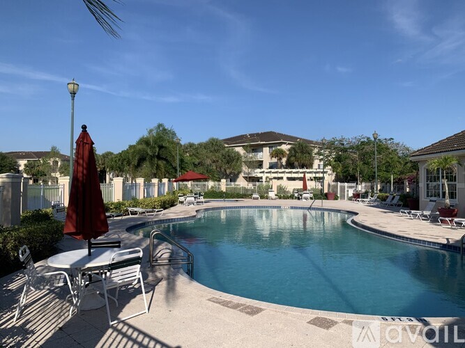 A pool area with sun loungers and a red umbrella.