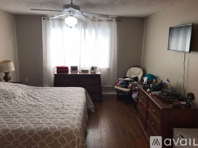 A bedroom with a bed, dresser, and window with curtains.