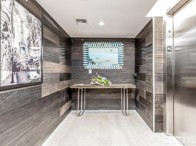 A modern hallway with a wooden floor and a metal bench.