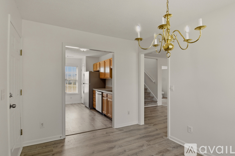 A chandelier hangs over a kitchen island with a sink and a refrigerator.