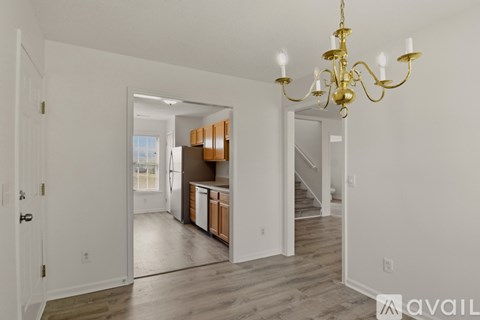 A chandelier hangs over a kitchen island with a sink and a refrigerator.