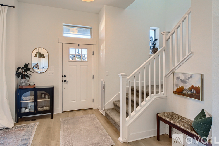 A hallway with a staircase, a bench, and a painting on the wall.