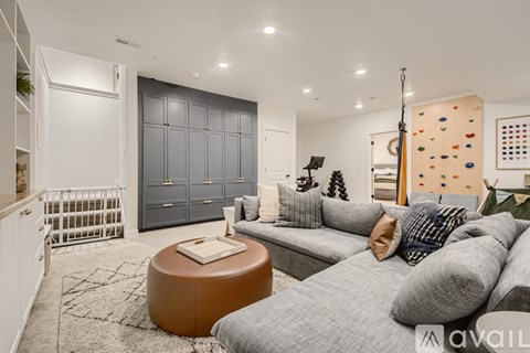 A living room with a grey couch and a brown ottoman.
