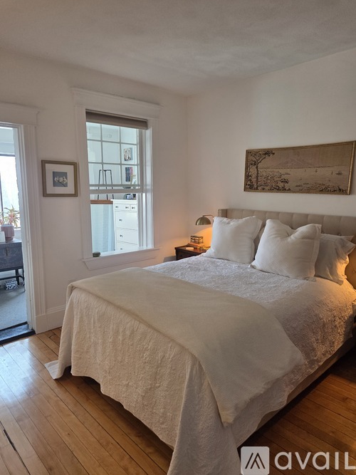 A bedroom with a large bed and a painting on the wall.