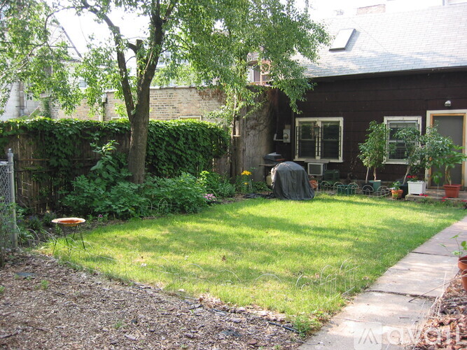 A backyard with a tree, a fence, and a small house.