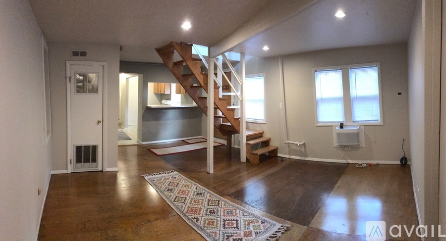 A living room with a staircase and a rug in the foreground.