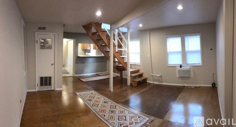 A living room with a staircase and a rug in the foreground.