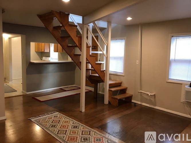 A wooden staircase with a white railing leads to a second floor.