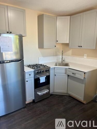 A kitchen with white cabinets and a stainless steel refrigerator.