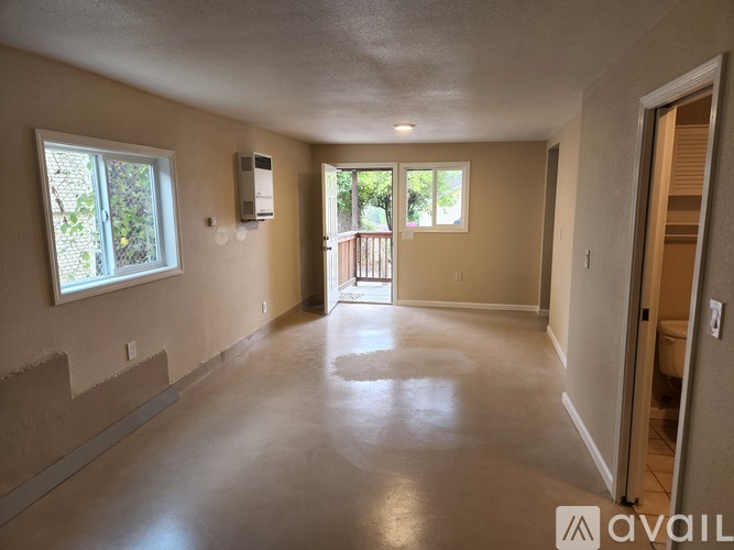 A spacious room with a window and a door leading to a balcony.