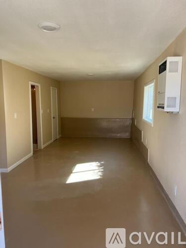 A spacious room with beige walls and a concrete floor.