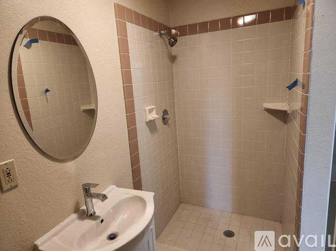 A bathroom with a white sink and a round mirror.
