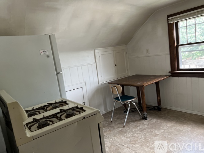 A kitchen with a white stove and a table with a chair.