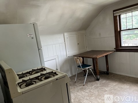 A kitchen with a white stove and a table with a chair.