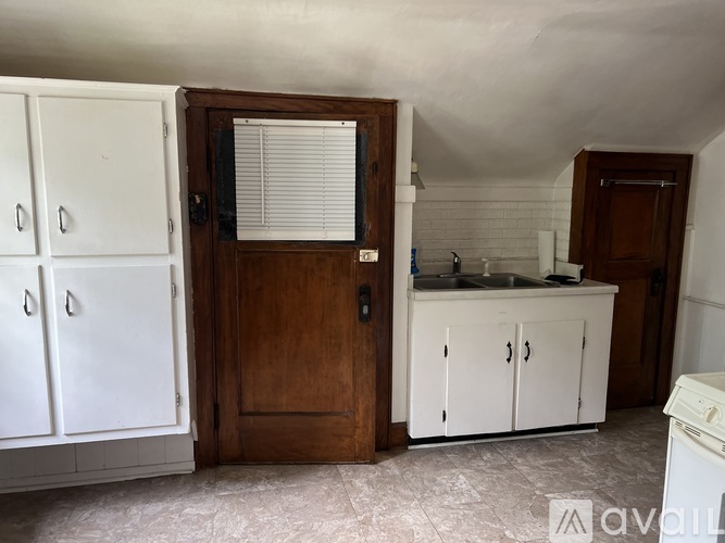 A kitchen with white cabinets and a wooden door.
