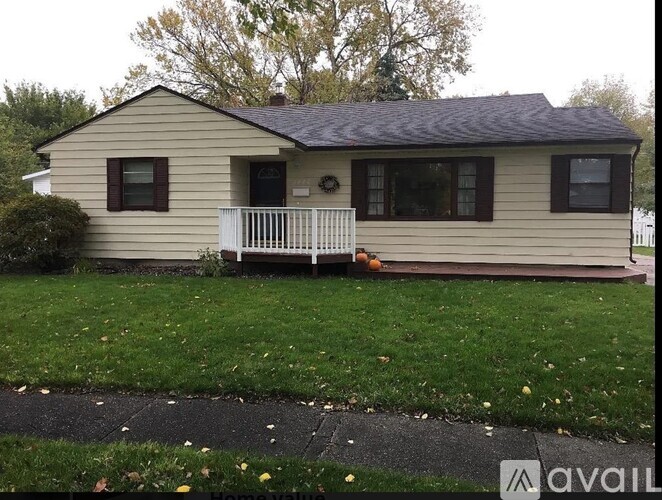 A small house with a porch and a white fence.