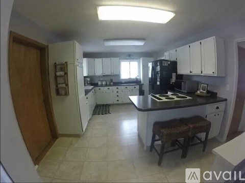 A kitchen with white cabinets and a black fridge.