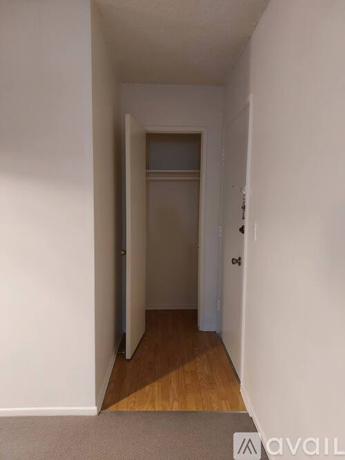 A hallway with a door on the right and a carpet on the floor.