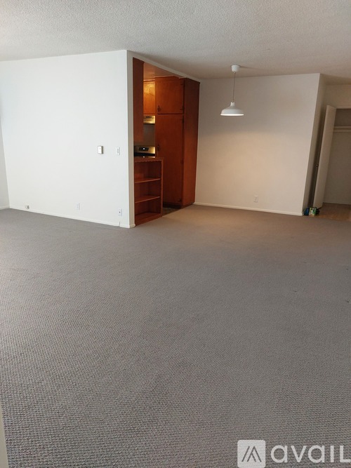 A room with a grey carpet and a white wall with a switchboard.