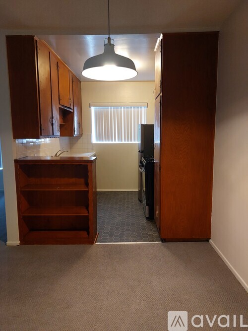 A kitchen area with a wooden cabinet and a hanging light fixture.