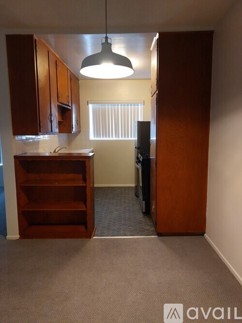 A kitchen area with a wooden cabinet and a hanging light fixture.