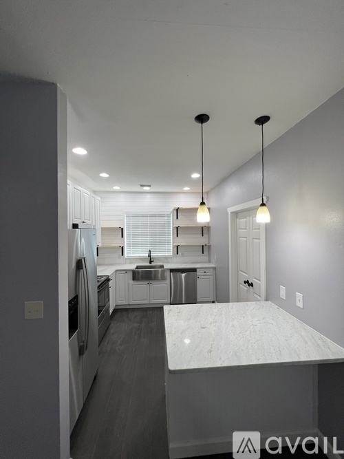 A kitchen with a marble countertop and pendant lights.
