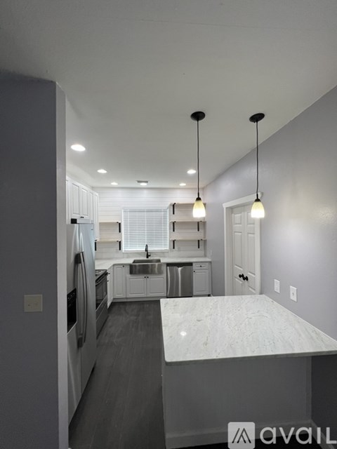 A kitchen with a marble countertop and pendant lights.