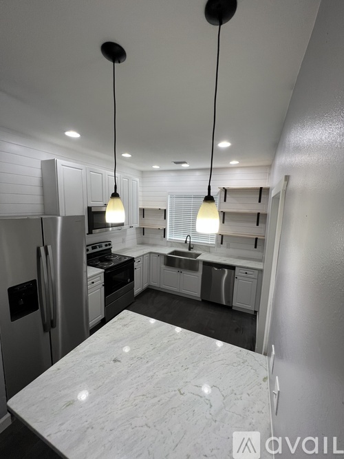 A modern kitchen with a marble countertop and stainless steel appliances.