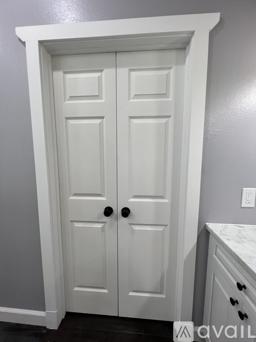 A white double door with a black handle is in a room.
