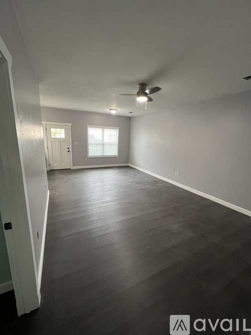 A spacious room with a ceiling fan and a door leading to another room.