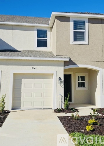 A beige house with a white garage door and a small window above it.