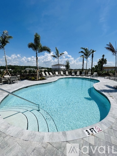 A swimming pool surrounded by palm trees and lounge chairs.