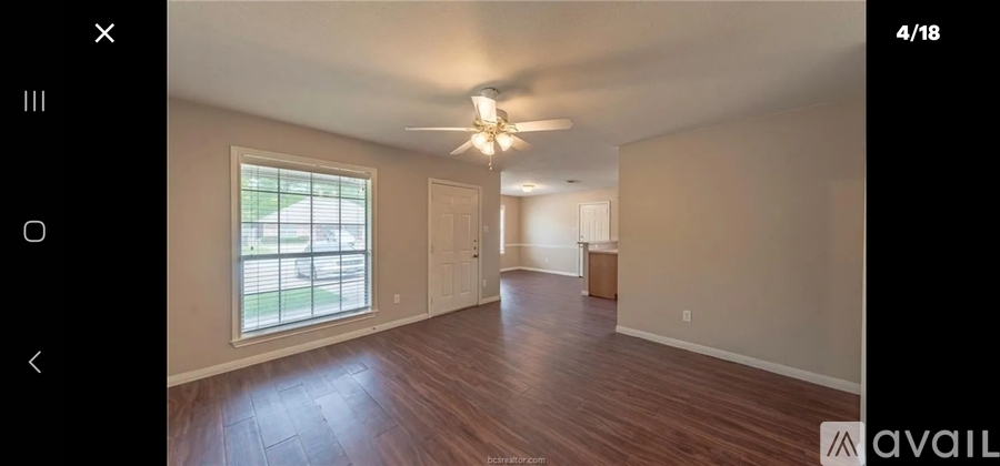 A spacious room with wooden floors and a ceiling fan.