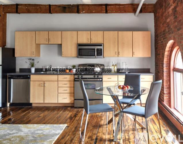 A kitchen with wooden cabinets and a brick wall.