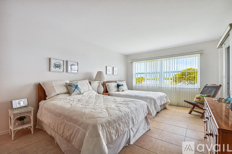 A bedroom with a large bed and a window with blinds.