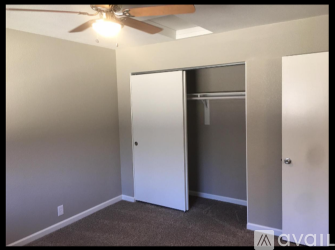 A room with a white door and a ceiling fan.