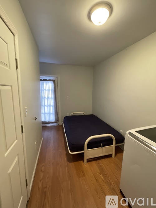 A bedroom with a bed, a washing machine, and a door.