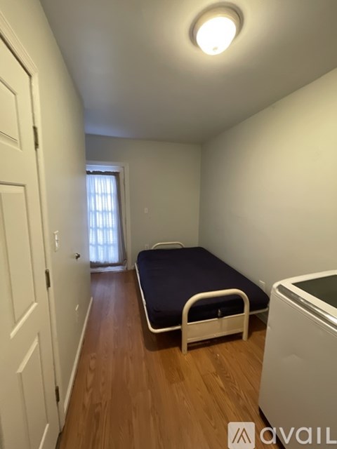A bedroom with a bed, a washing machine, and a door.