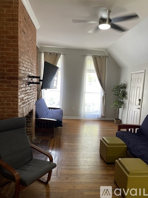 A living room with a brick wall and a ceiling fan.