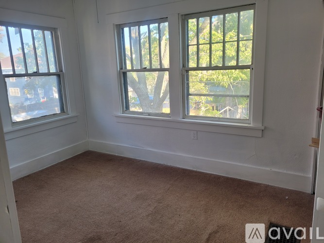 A room with two windows and carpeted floor.