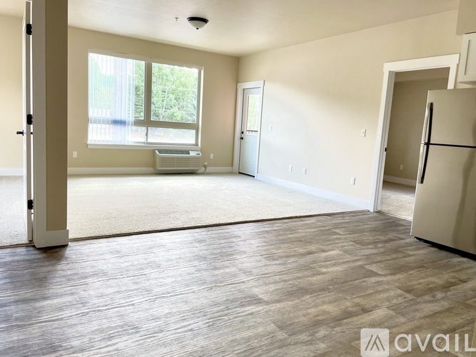 A spacious living room with a refrigerator in the corner.