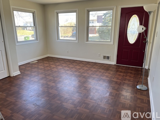 A room with a red door and wooden flooring.