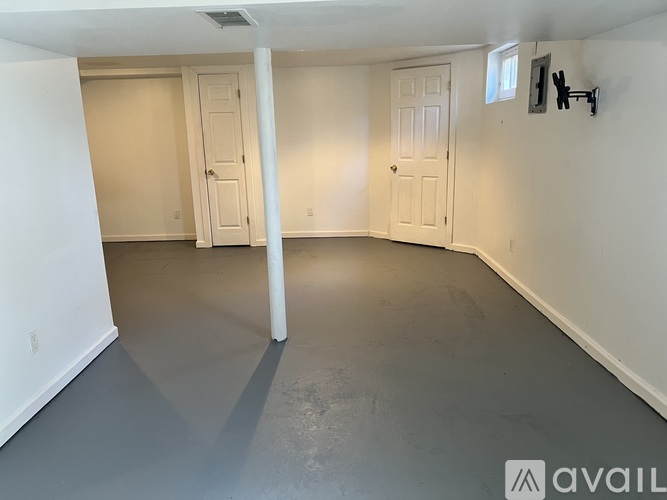 A spacious empty room with white walls and a grey floor.