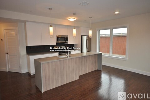 A modern kitchen with a wooden island and a microwave above it.