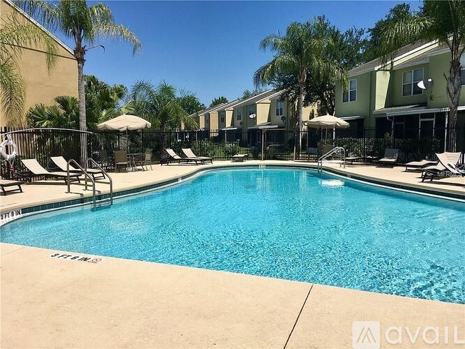 A swimming pool surrounded by lounge chairs and palm trees.